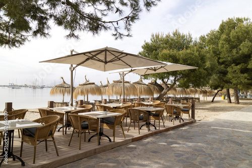 Porto Pollensa, Mallorca, Spain. 2018. Beachside tables and chairs set for breakfast in an early morning light.