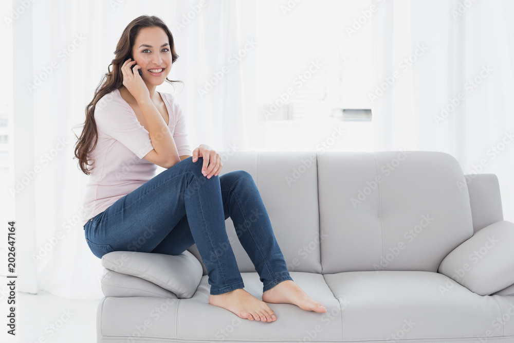 Relaxed young woman using cellphone on sofa at home Relaxed young woman using cellphone on sofa at home