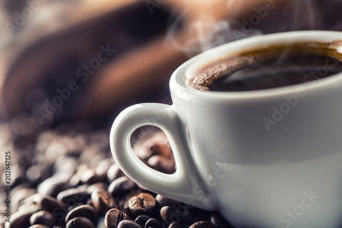Fototapeta Filiżanka czarnej kawy z ziarnami na drewnianym stole XXL