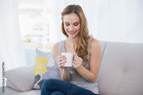 Content young woman sitting on sofa holding mug