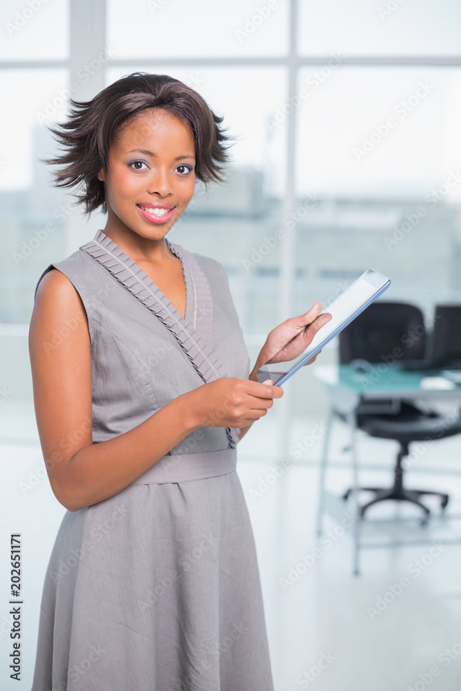 Attractive businesswoman standin in her office holding tablet Attractive businesswoman standin in her office holding tablet