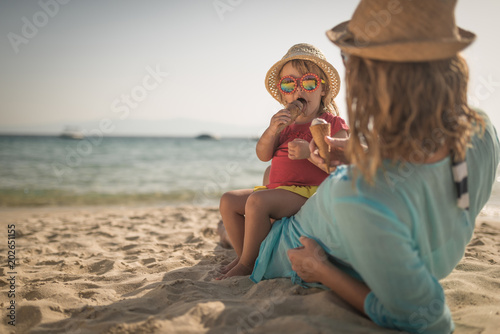 Mother with child on tropical beach ieating icecream photo