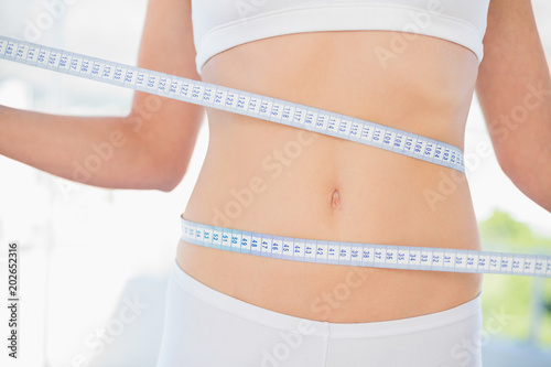 Slender woman measuring her waist during diet