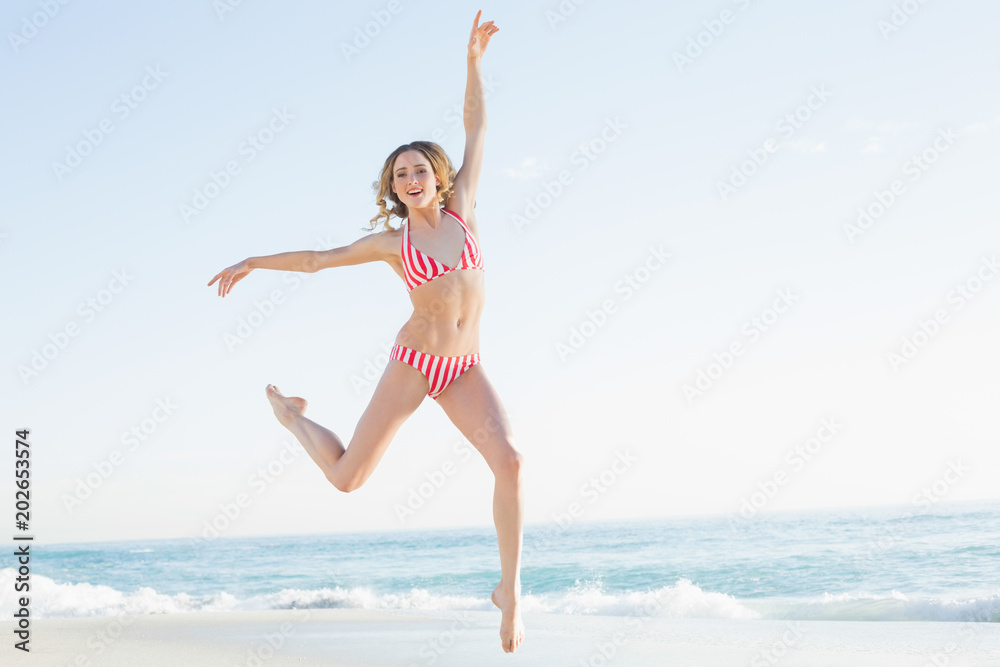Lovely young woman jumping on the beach 