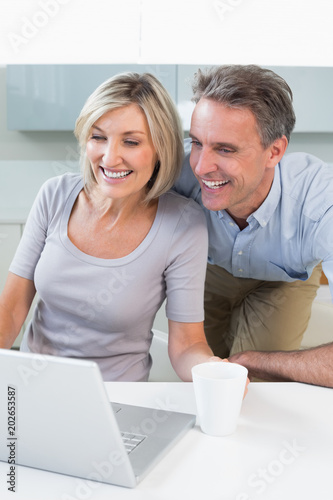 Happy casual couple using laptop in kitchen © WavebreakmediaMicro