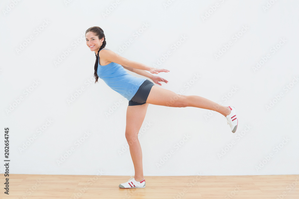Woman standing on one leg in fitness center