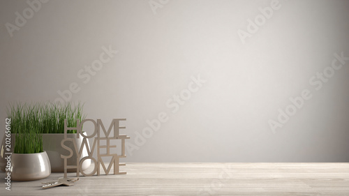 Wooden table, desk or shelf with potted grass plant, house keys and 3D letters making the words home sweet home, white blank copy space background photo
