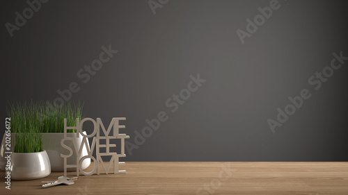 Wooden table, desk or shelf with potted grass plant, house keys and 3D letters making the words home sweet home, gray copy space background photo