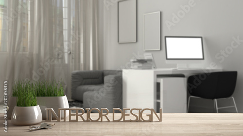 Wooden table  desk or shelf with potted grass plant  house keys and 3D letters making the words interior design  over blurred modern workplace  project concept copy space background