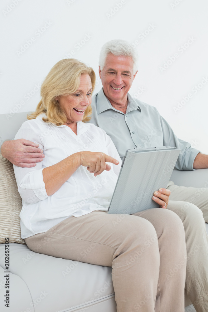 Relaxed senior couple using digital tablet on sofa