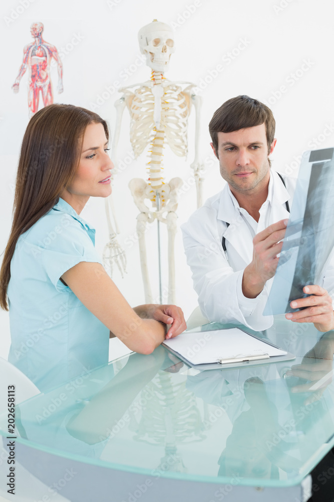 Obraz premium Male doctor explaining spine xray to female patient