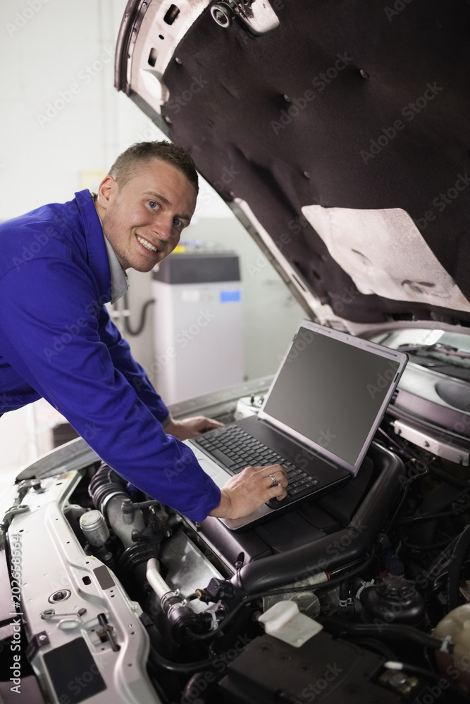Smiling mechanic working on a computer Smiling mechanic working on a computer