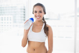 Smiling sporty brunette holding a water bottle