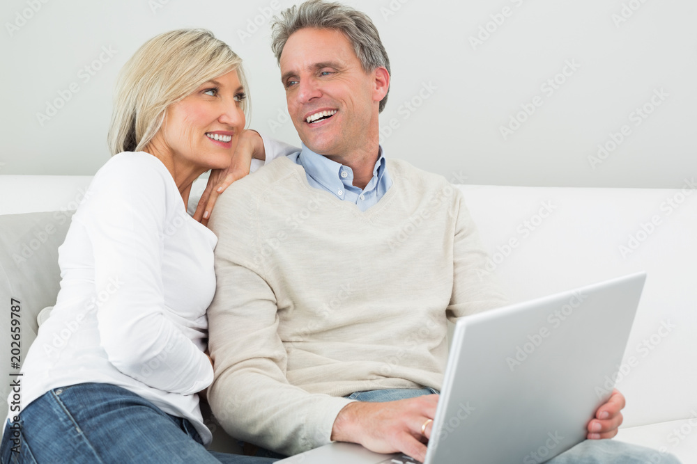 Happy casual couple using laptop in at home