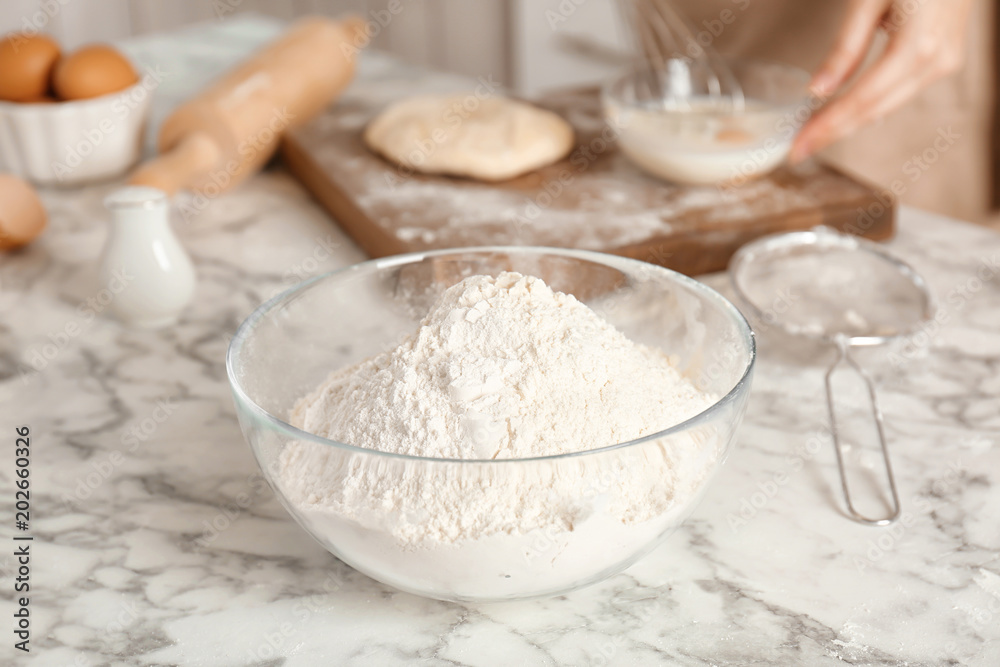 Bowl with flour and woman on background Bowl with flour and woman on background