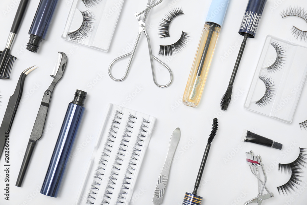 Flat lay composition with false eyelashes and cosmetic tools on white background