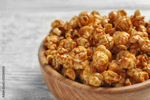Delicious popcorn with caramel in bowl on table, closeup