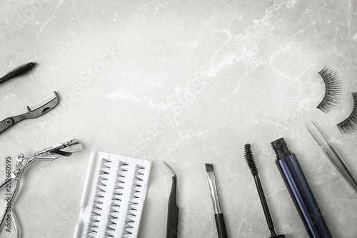 Flat lay composition with false eyelashes and cosmetic tools on light background