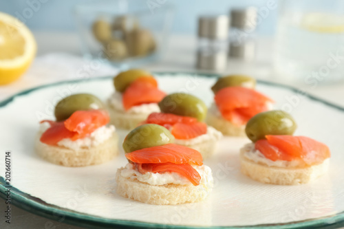 Tasty sandwiches with fresh sliced salmon fillet and olives on plate, closeup