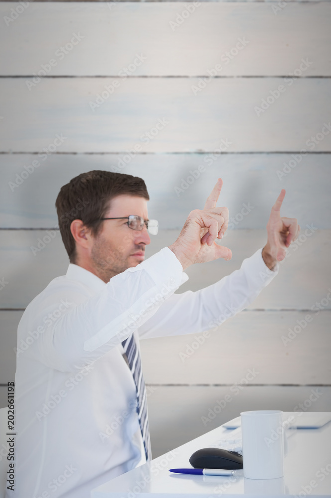 Businessman holding hands up at desk against wooden planks Businessman holding hands up at desk against wooden planks