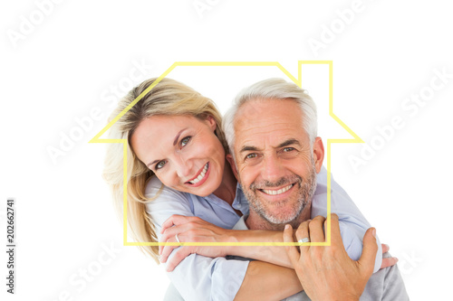 Happy couple standing and hugging against house outline