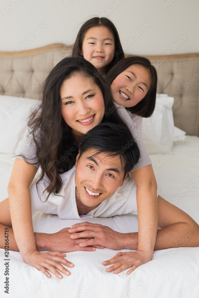 Cheerful family of four lying over each other in bed Cheerful family of four lying over each other in bed