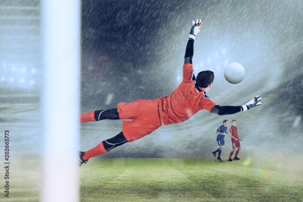 Fit goal keeper jumping up against football stadium Fit goal keeper jumping up against football stadium