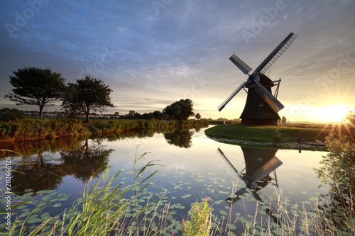 beautiful sunrise over windmill by river