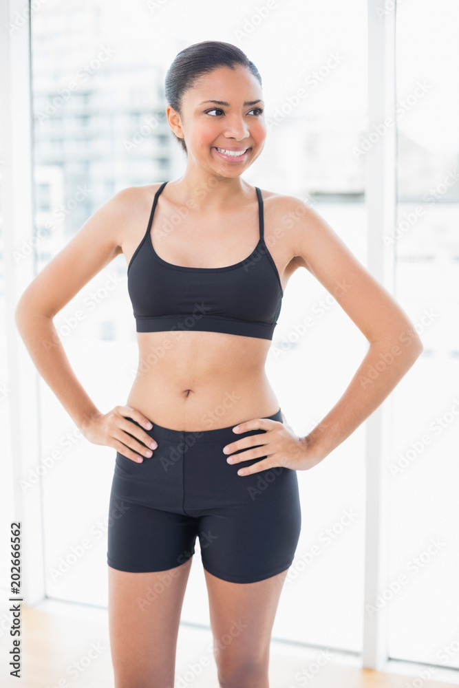 Amused dark haired model in sportswear posing with hands on the hips