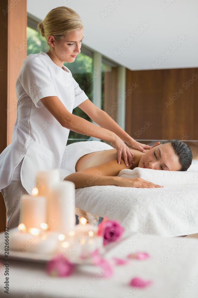 Smiling brunette getting a shoulder massage Smiling brunette getting a shoulder massage