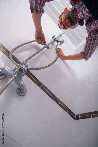 plumber repairing shower head in bathroom