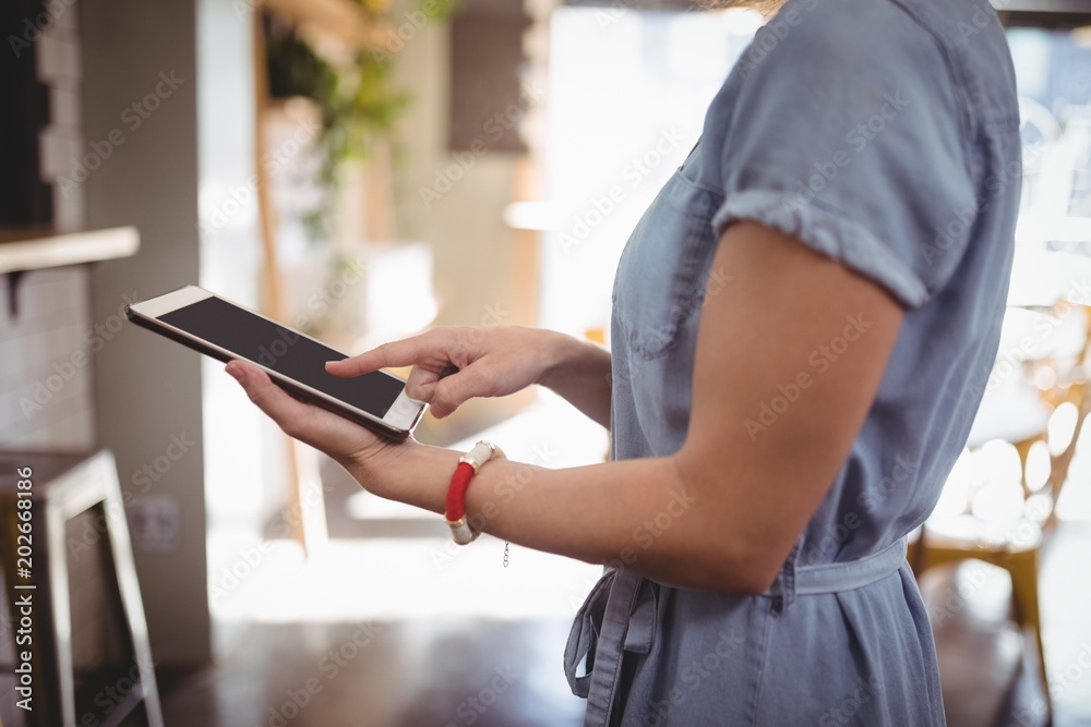 Midsection of woman scrolling digital tablet