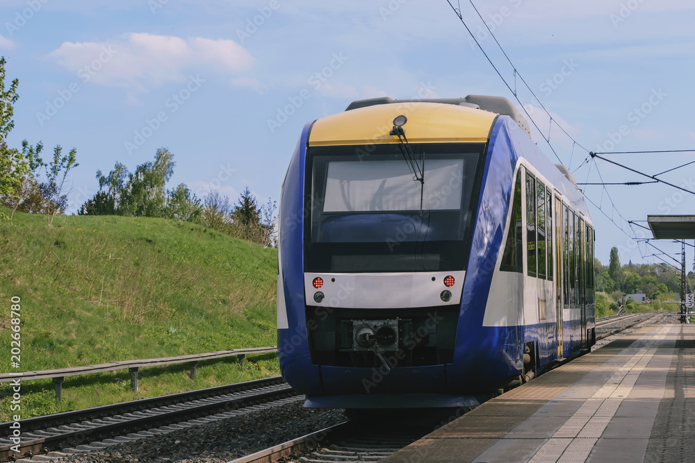 Naklejka premium short passenger train stands on a deserted platform in a picturesque countryside