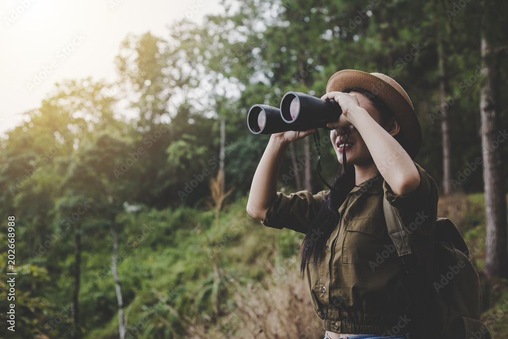 Asia woman traveler with Binoculars and in Forest,Travel concept.