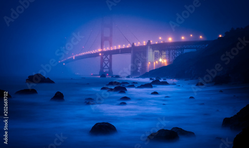 Twilight fades to night as the lights of the Golden Gate bridge emerge from the fog.