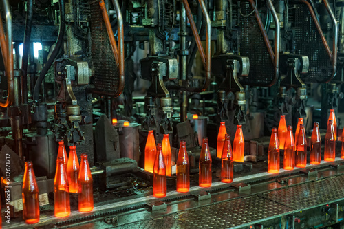 Automated line for the production of glass containers. The hot bottles are put on a moving conveyor