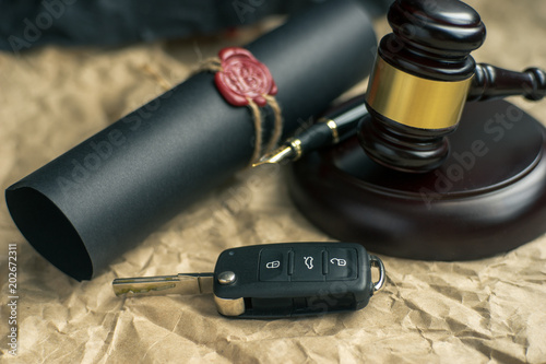 Close-up Of Gavel And Car Key On Sounding Block Against Grey Background photo