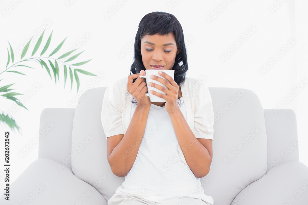 Natural black haired woman in white clothes enjoying coffee