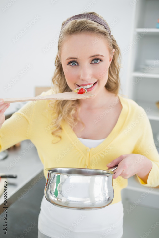 Cheerful cute blonde tasting food from wooden spoon Cheerful cute blonde tasting food from wooden spoon