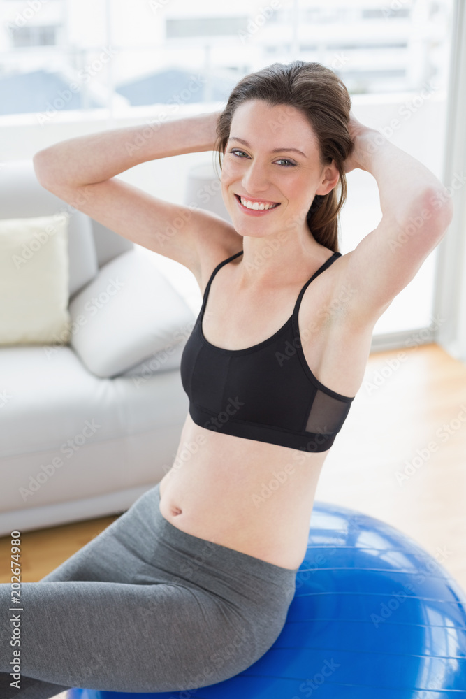 Fit woman sitting on exercise ball in fitness studio