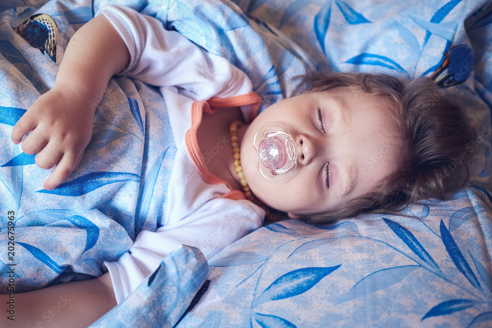 Cute little boy is sleeping in bed and sucking a pacifier. Top view. Cute little boy is sleeping in bed and sucking a pacifier. Top view.