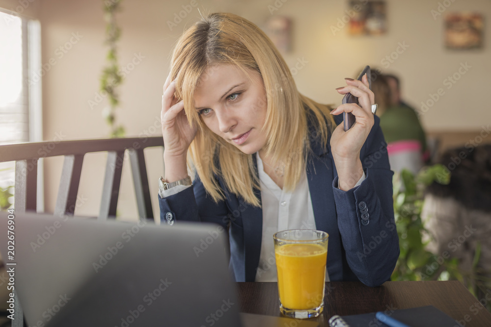 Young business woman using her laptop computer and holding smart phone Young business woman using her laptop computer and holding smart phone