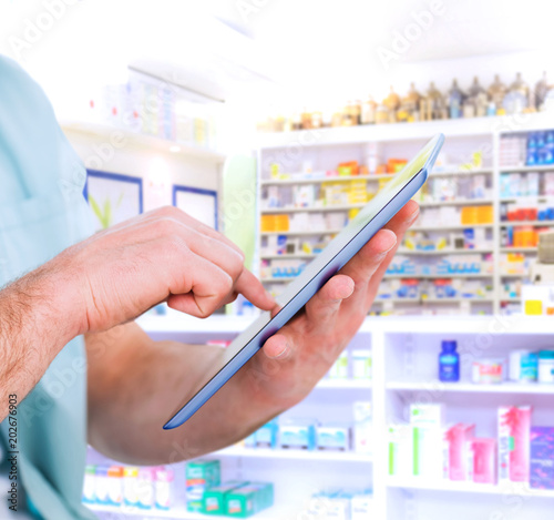 Man using tablet pc against close up of shelves of drugs