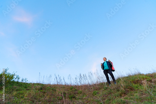 Hikking female with stick stay on mountain and staring into the distance