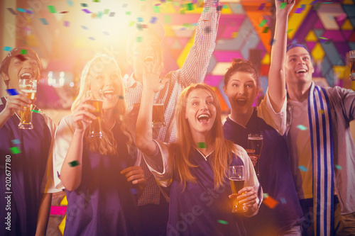 Group of friends cheering in party while having glass of champagne against flying colours