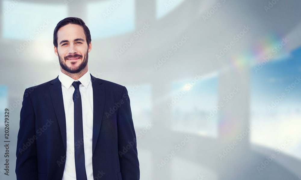 Smiling businessman in suit standing with hands in pockets against bright white room with windows Smiling businessman in suit standing with hands in pockets against bright white room with windows