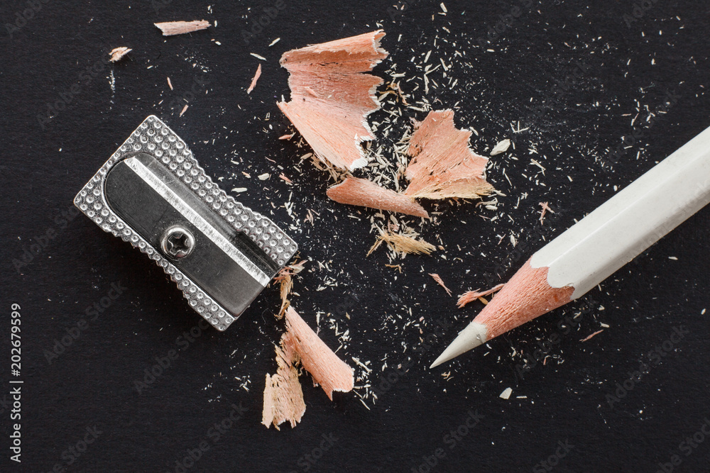 Φωτογραφία white wooden pencil, sharpener and pencil shavings on black