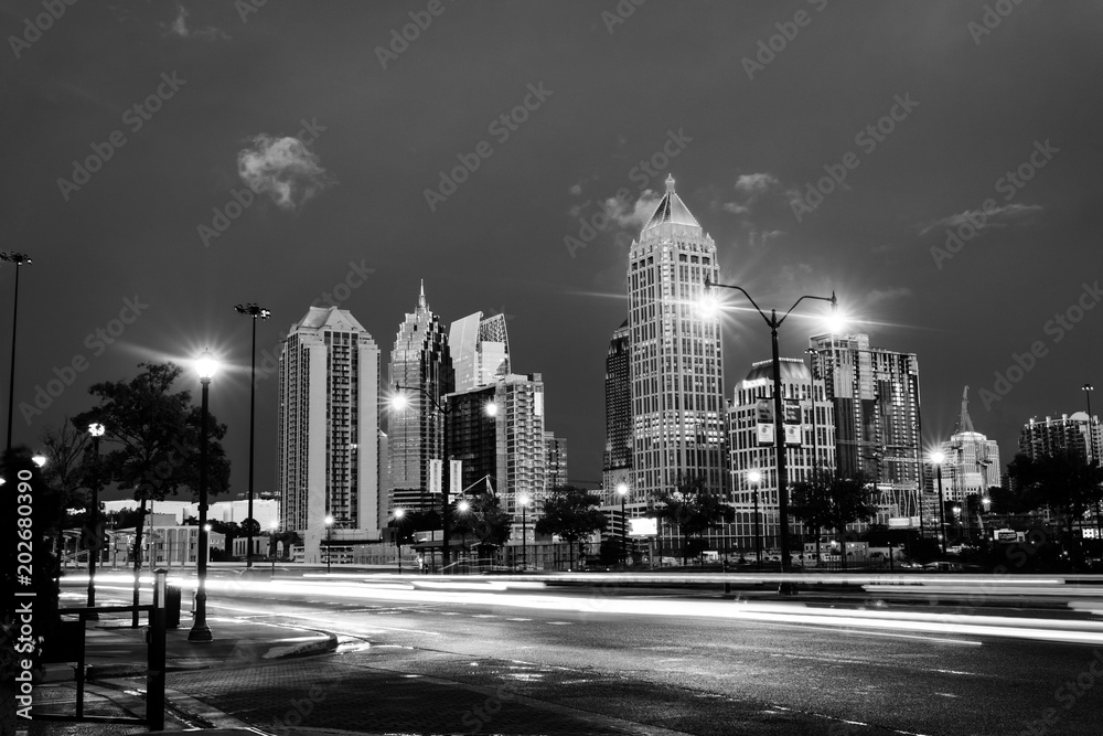 Illuminated Midtown in Atlanta, USA at night. Car traffic, illuminated buildings and dark sky. Black and white - obrazy, fototapety, plakaty 