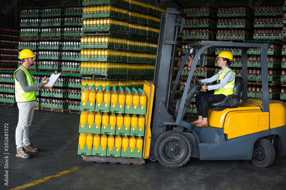 Fototapeta premium Male factory worker maintaining record on clipboard in drinks production factory