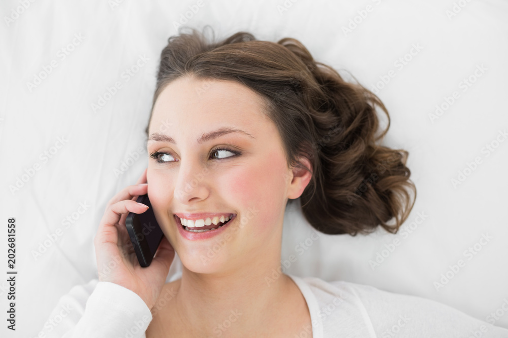 Young brunette using mobile phone in bed Young brunette using mobile phone in bed